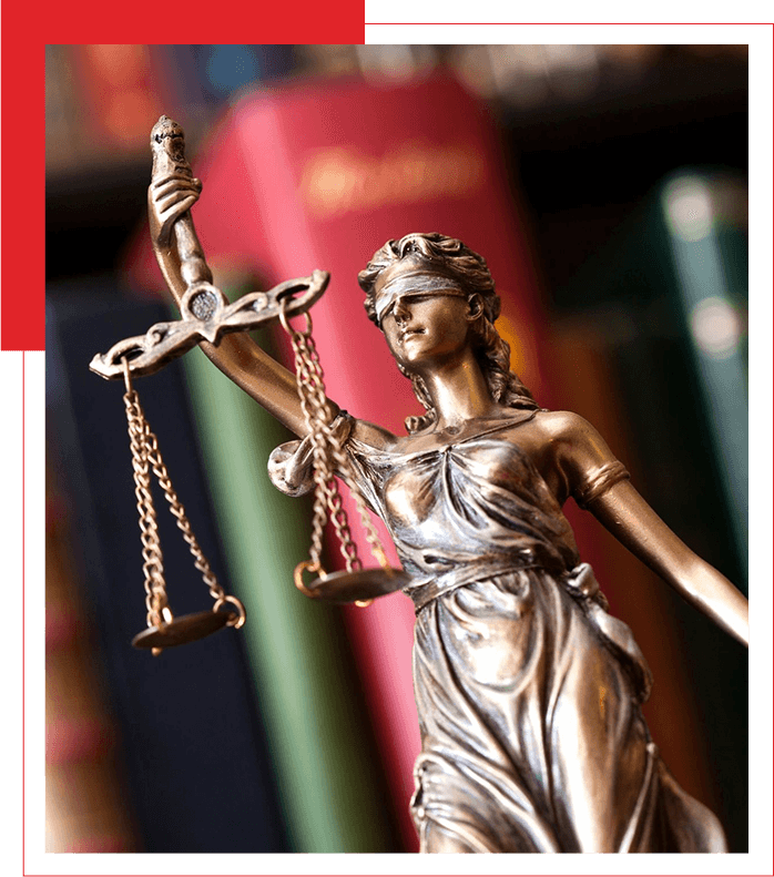 Statue of lady justice in front of a bookshelf with legal volumes.