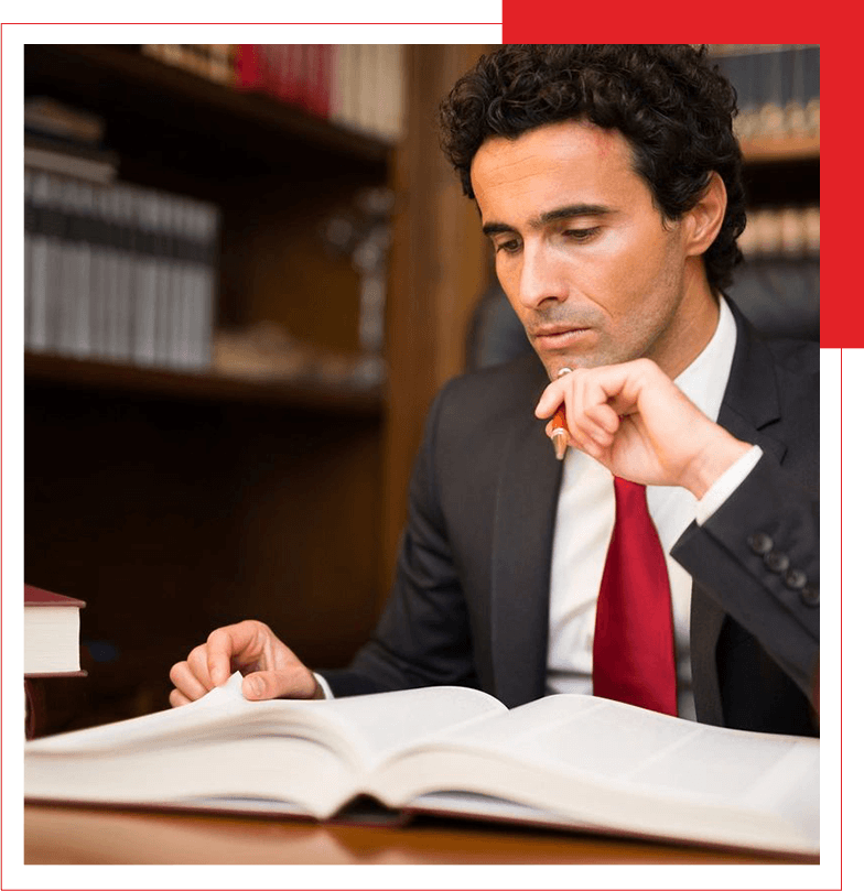 A concentrated individual reading a book in a library setting.