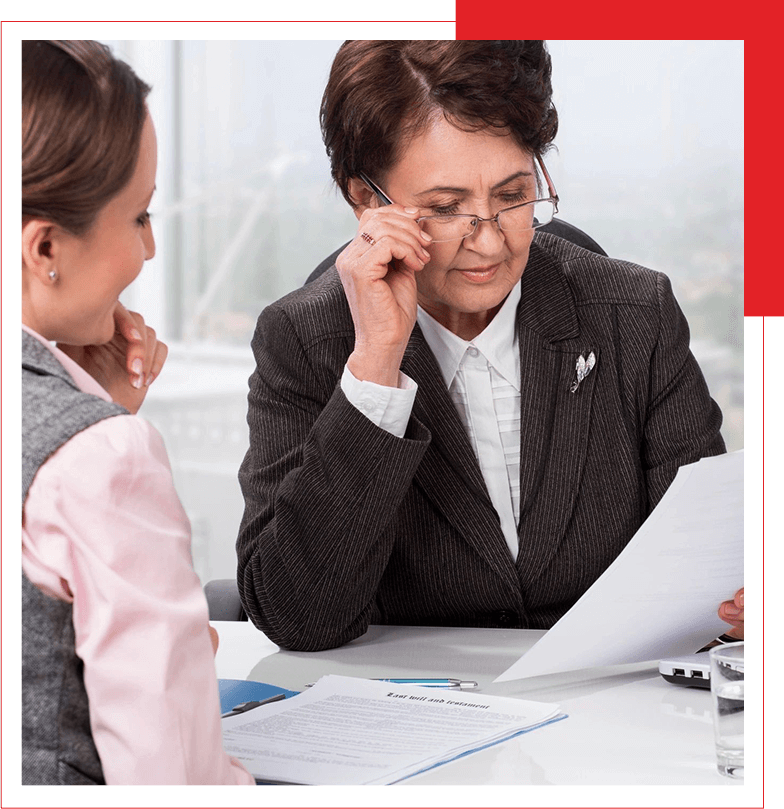 A senior businesswoman reviewing a document with a female colleague in an office setting.