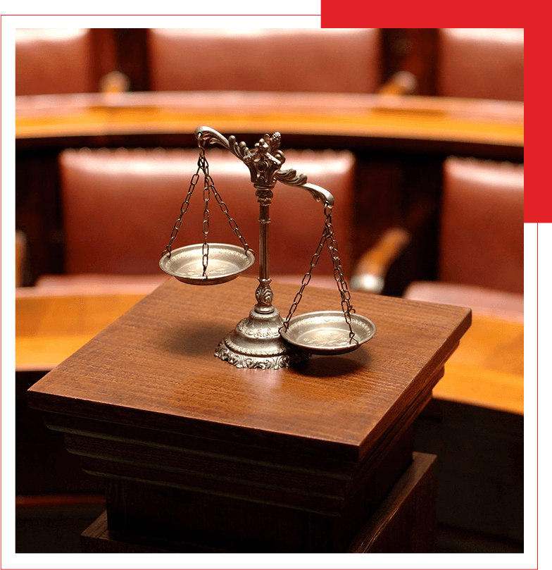 A close-up of a traditional balance scale on a wooden stand in a courtroom setting.