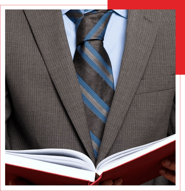 A person in a pinstriped suit with a blue tie reading an open book.