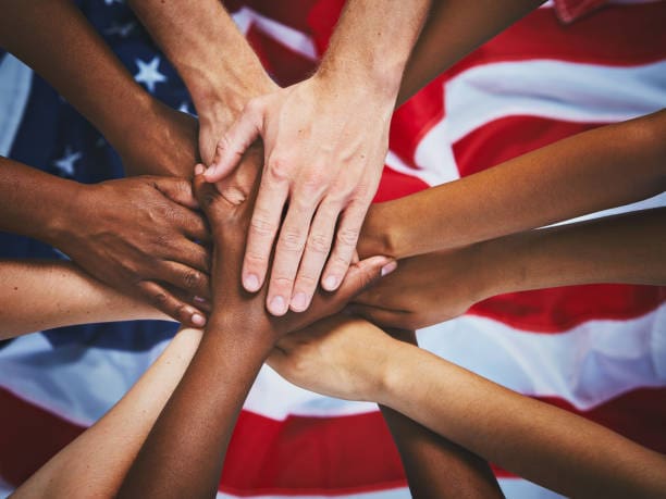 A dozen mixed hands stacked up on top of the American national flag. A dozen mixed hands stacked up on top of the American national flag.